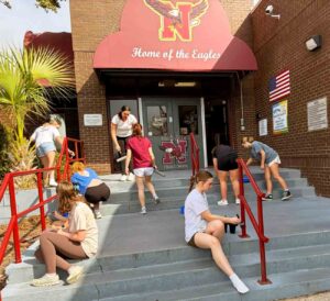 Niceville High School Tri-M Honor Society students work on a campus beautification project near a school entrance.