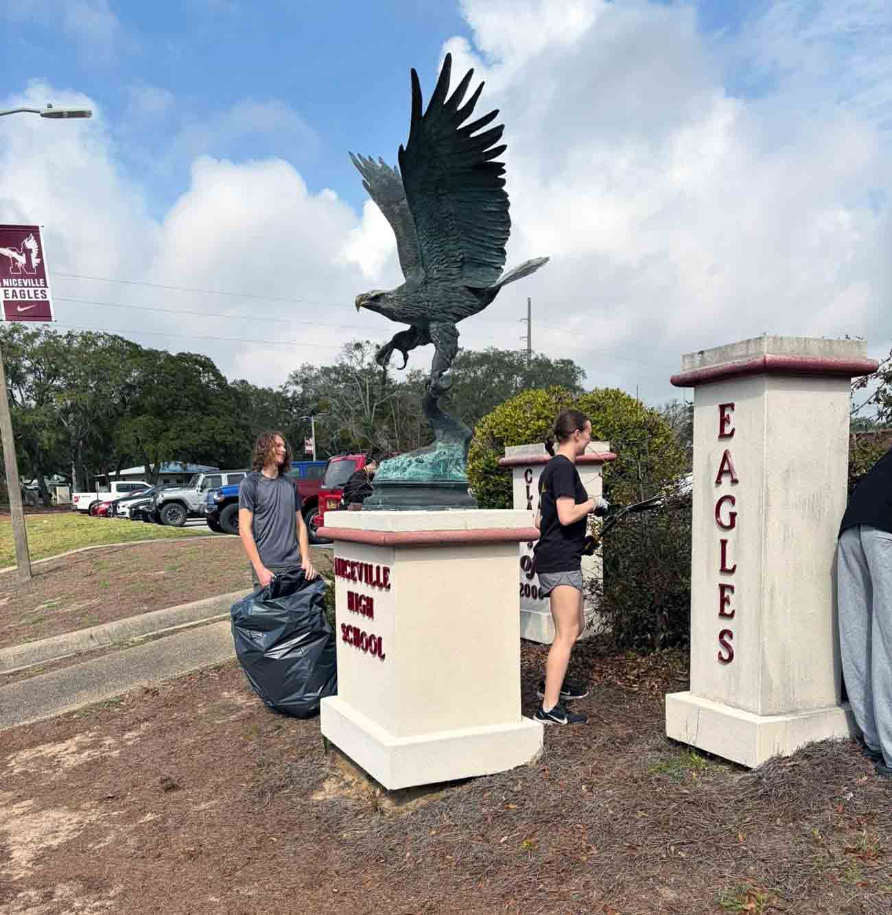 Niceville High School students clean landscaping near the school’s eagle monument during a service project.