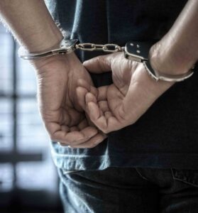 Person with hands behind back in handcuffs.