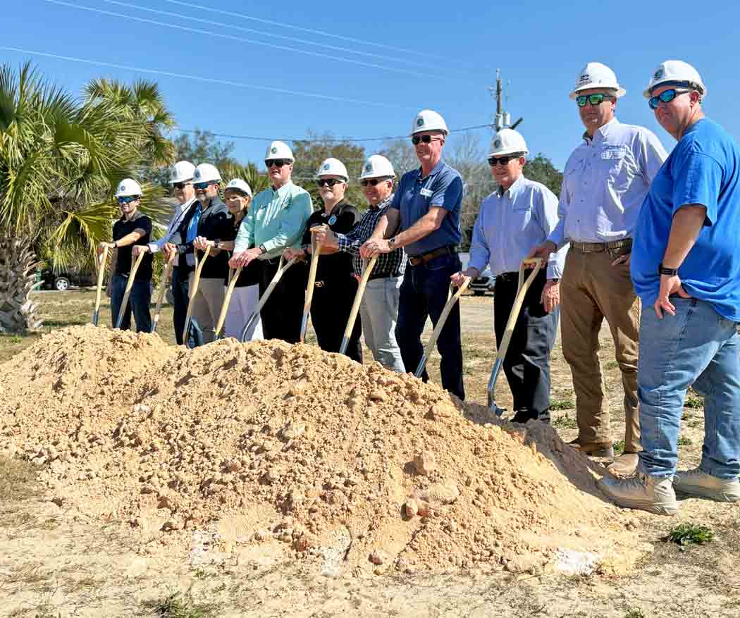 Niceville city and county officials wearing white hard hats hold ceremonial shovels during the Old Town Landing dock and pier groundbreaking ceremony.