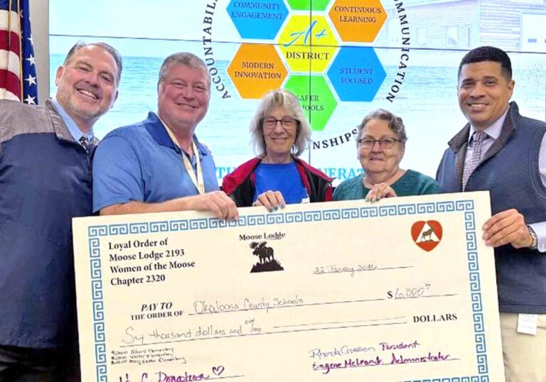 Okaloosa County School District leaders and Moose Lodge members hold a ceremonial $6,000 donation check for student lunch debt