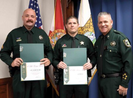 Two Okaloosa County Sheriff’s Office deputies receive Life Saving Awards while standing with Sheriff Eric Aden.