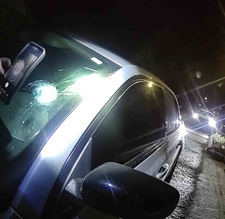 Bullet hole visible in windshield of vehicle stopped at night along State Road 85 near Shoal River Bridge.