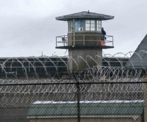 Prison guard tower behind barbed wire fencing at correctional facility