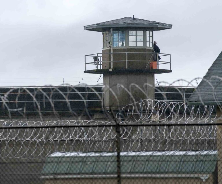 Prison guard tower behind barbed wire fencing at correctional facility