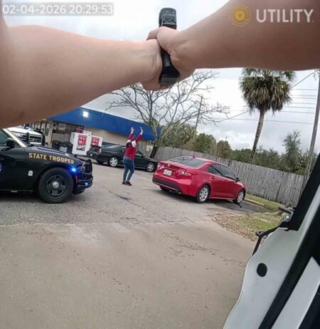 Law enforcement officers conduct a felony traffic stop as a woman stands with her hands raised near a red sedan and a marked Florida Highway Patrol vehicle.