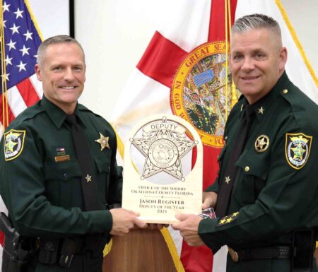 Okaloosa County Sheriff Eric Aden presents Deputy Jason Register with the 2025 Deputy of the Year award during a recognition ceremony.