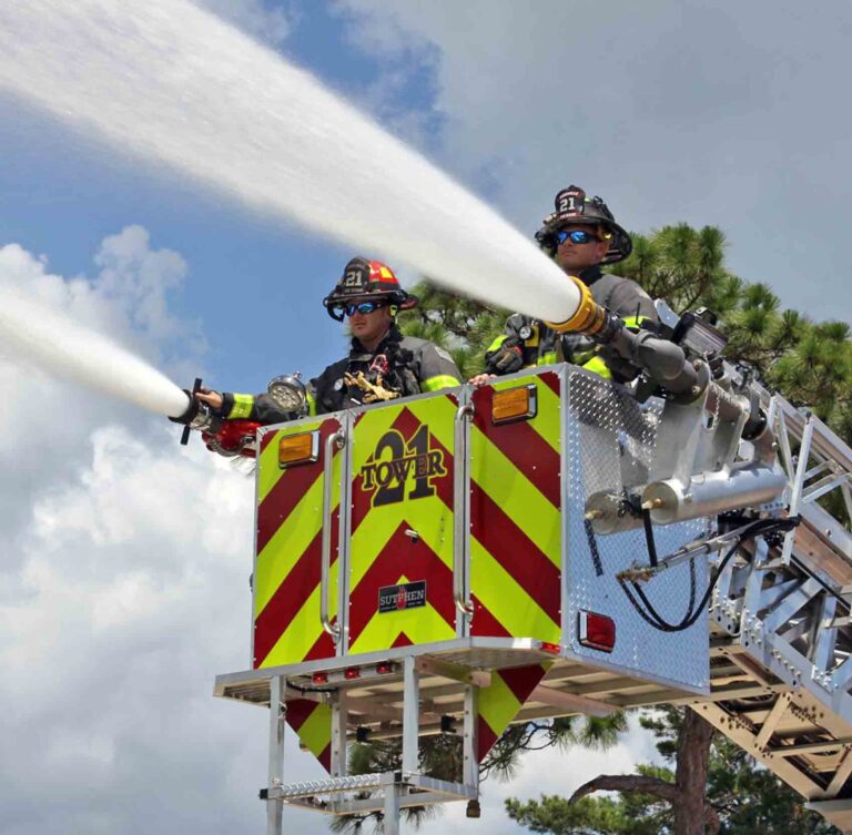Firefighters operating Tower 21 ladder truck spraying water during training or response
