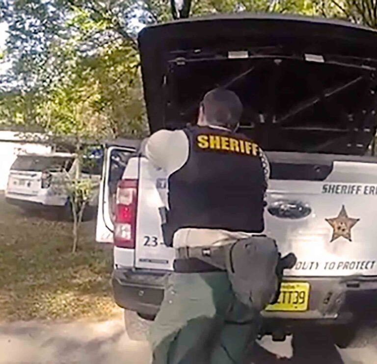 Okaloosa County Sheriff’s Office deputy taking cover behind a patrol vehicle during a response in a residential area