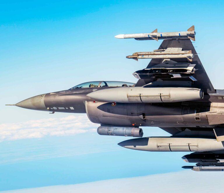 F-16 Fighting Falcon flying with multiple externally mounted munitions during test operations