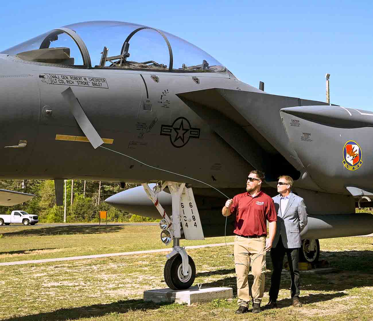 Officials stand beside an F-15E Strike Eagle during a dedication ceremony at the Air Force Armament Museum