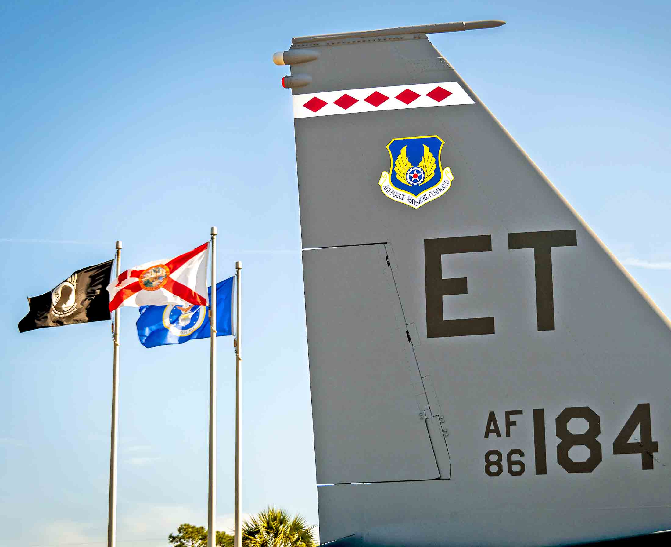 Tail of an F-15E Strike Eagle displayed at the Air Force Armament Museum with flags flying nearby
