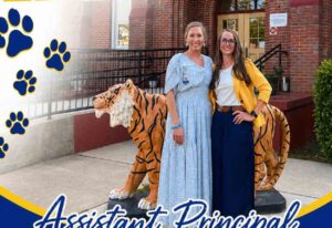 Two women stand in front of Lula J. Edge Elementary School in Niceville beside a tiger statue, with a welcome message announcing Assistant Principal Goss.