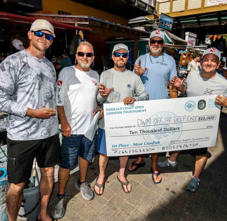 Members of the DWM Off the Deep End dive team pose with a ceremonial $10,000 check after winning first place for harvesting the most lionfish during the 2026 Emerald Coast Open lionfish tournament in Destin-Fort Walton Beach.