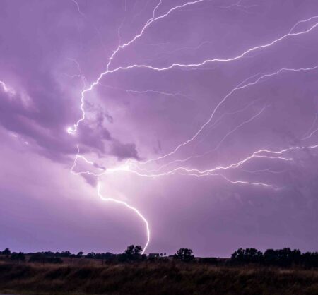 Lightning safety Q&A: UF/IFAS experts share lifesaving advice A bright cloud-to-ground lightning strike branches across a stormy purple sky above a rural landscape at night.