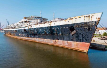 SS United States reef deployment set for Nov. 12 off Destin The historic SS United States ocean liner, showing extensive rust along its black-and-white hull, docked ahead of its scheduled November 12, 2026, deployment as an artificial reef off Destin-Fort Walton Beach, Florida.